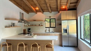 A modern kitchen with wooden beams, a large island with bar stools, and a stainless steel refrigerator. - Private Miami home retreat with Oak Tree Deck & Gated Yard / 3 beds, 2 baths (Miami)