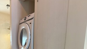 A laundry room with two stacked washing machines and a vent. - Private Miami home retreat with Oak Tree Deck & Gated Yard / 3 beds, 2 baths (Miami)