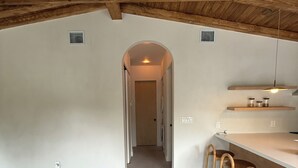 An interior with a high ceiling, a kitchen area with bar stools, and a hallway leading to another room. - Private Miami home retreat with Oak Tree Deck & Gated Yard / 3 beds, 2 baths (Miami)