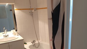 Un bagno con una vasca, una doccia, un lavandino con uno specchio e un porta asciugamani.