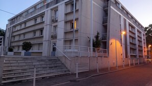 Un edificio a più piani con una scala che conduce all'ingresso, un balcone al secondo piano e una scala antincendio sul lato.
