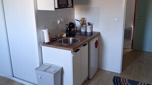 Una cucina compatta con forno a microonde, lavello e piccolo frigorifero.