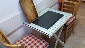 Ein kleiner Essbereich mit einem Tisch, zwei Stühlen, einer Holzbank und einem an der Wand befestigten Telefon.