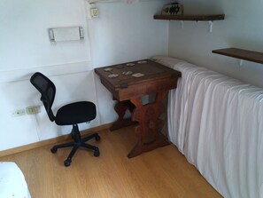 A small room with a wooden desk, a black office chair, a white bed, and a white curtain. - One apartment - A lot of beds at Palermo Hollywood - Fully equiped - ב''ה (Buenos Aires)