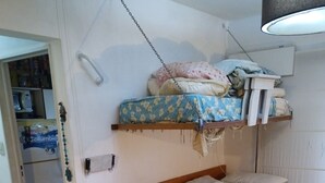 Ein gemütlicher Raum mit einem Etagenbett, einem Einzelbett, einem kleinen Tisch mit einer Karte und einer Tür zu einer Küchenzeile.