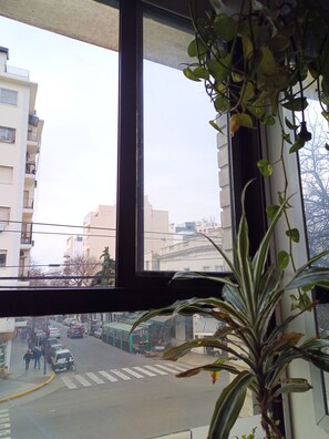 A view from inside a building looking out through a window at a street with buildings and parked cars. - One apartment - A lot of beds at Palermo Hollywood - Fully equiped - ב''ה (Buenos Aires)