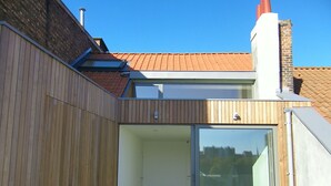 A modern building with a wooden exterior, a glass door leading to an interior space, and a red-tiled roof. - Abbaye de la Cambre • Private Mansion • 469 m• Lift &  AIR CO , Min 92 nights (Ixelles)
