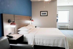 Ein Hotelzimmer mit Bett, Nachttisch, Lampe und einem gerahmten Bild an der Wand.