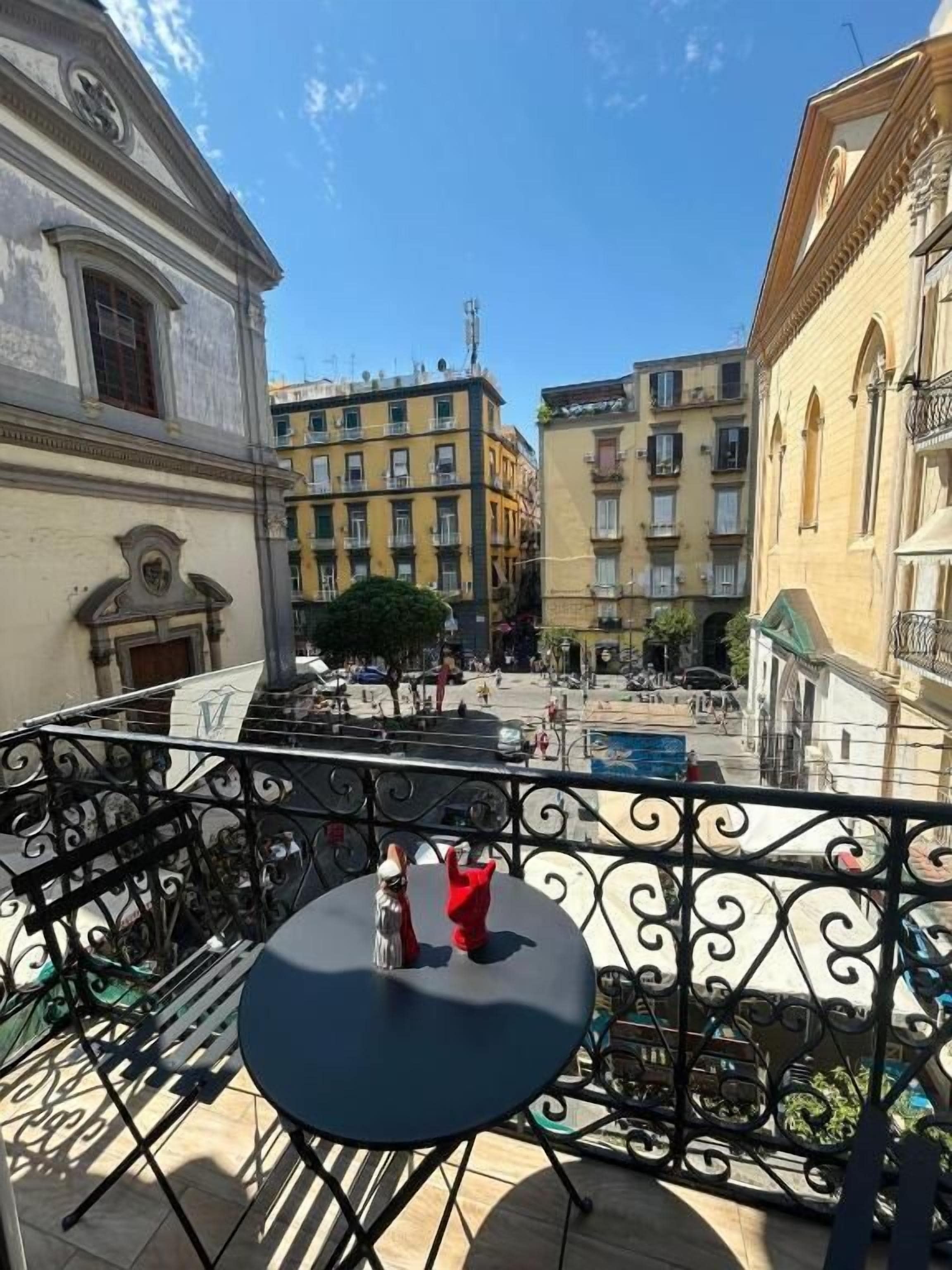 Un patio con una mesa redonda y sillas, rodeado de edificios con balcones.