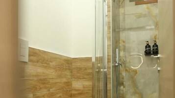 Un bagno con doccia vetrata, un water e un rivestimento in marmo.