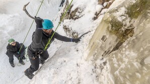 En person som förankrad i ett rep för nedför en snötäckt sluttning.