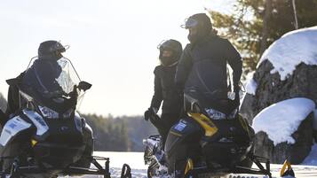 Three snowmobiles on a snowy surface with a clear sky in the background.