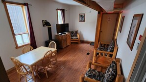 Ett mysigt rum med ett träbord, stolar, en soffa, en öppen spis och en dörr med en skylt.
