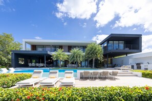 A modern two-story house with a swimming pool, outdoor seating, and a covered patio area. - Villa Coral Breeze | Luxury Villa | Private Beach (Willemstad)