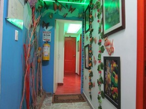 A hallway with a red door at the end, decorated with butterflies and flowers. - Hotel Apartasuite Normandia (Bogotá)