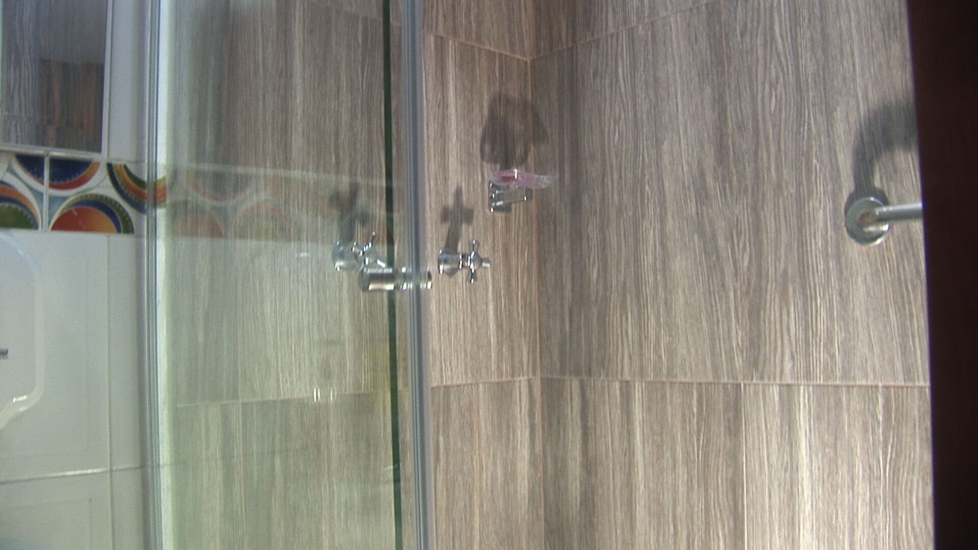 Un baño con cabina de ducha de vidrio y piso de madera.