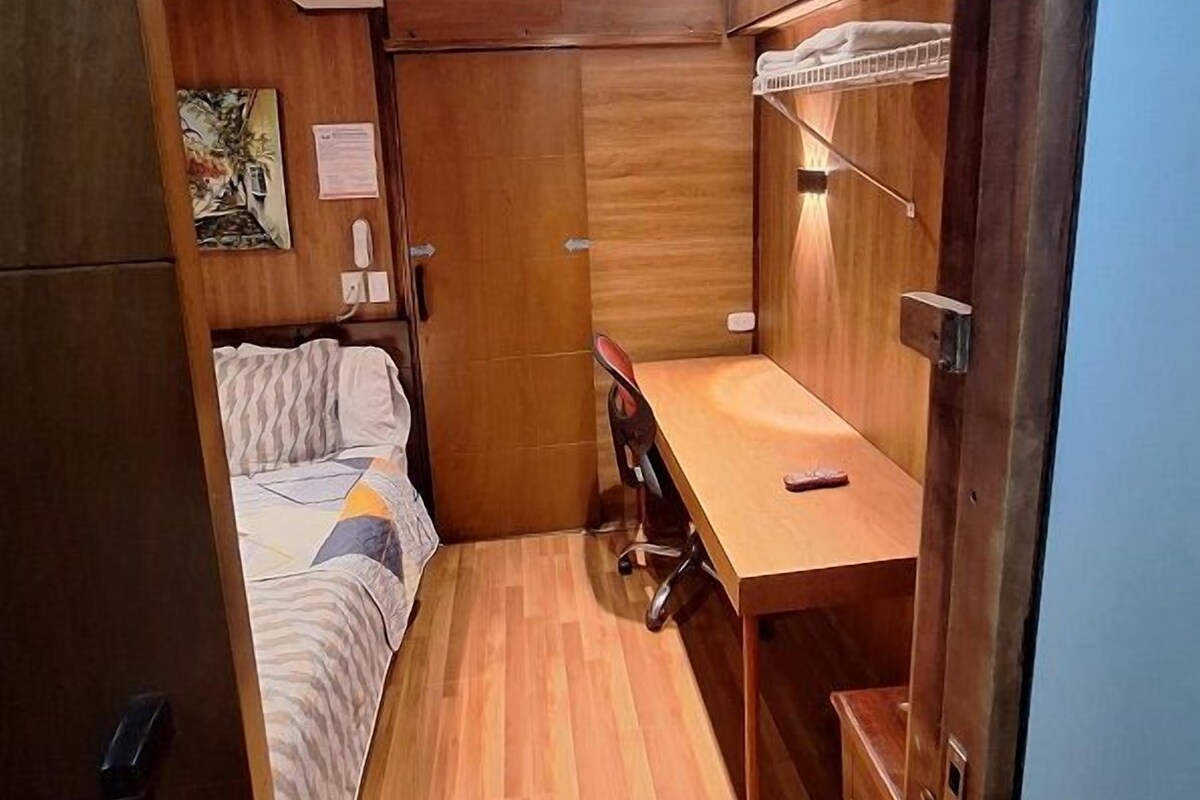 A compact room with a bed, a desk, and a wardrobe.
