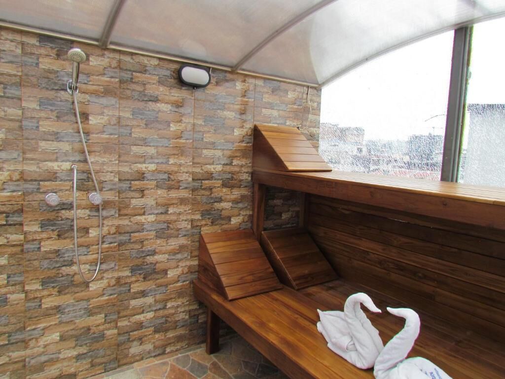 Una sauna con pared de piedra, bancos de madera y un banco con toalla.