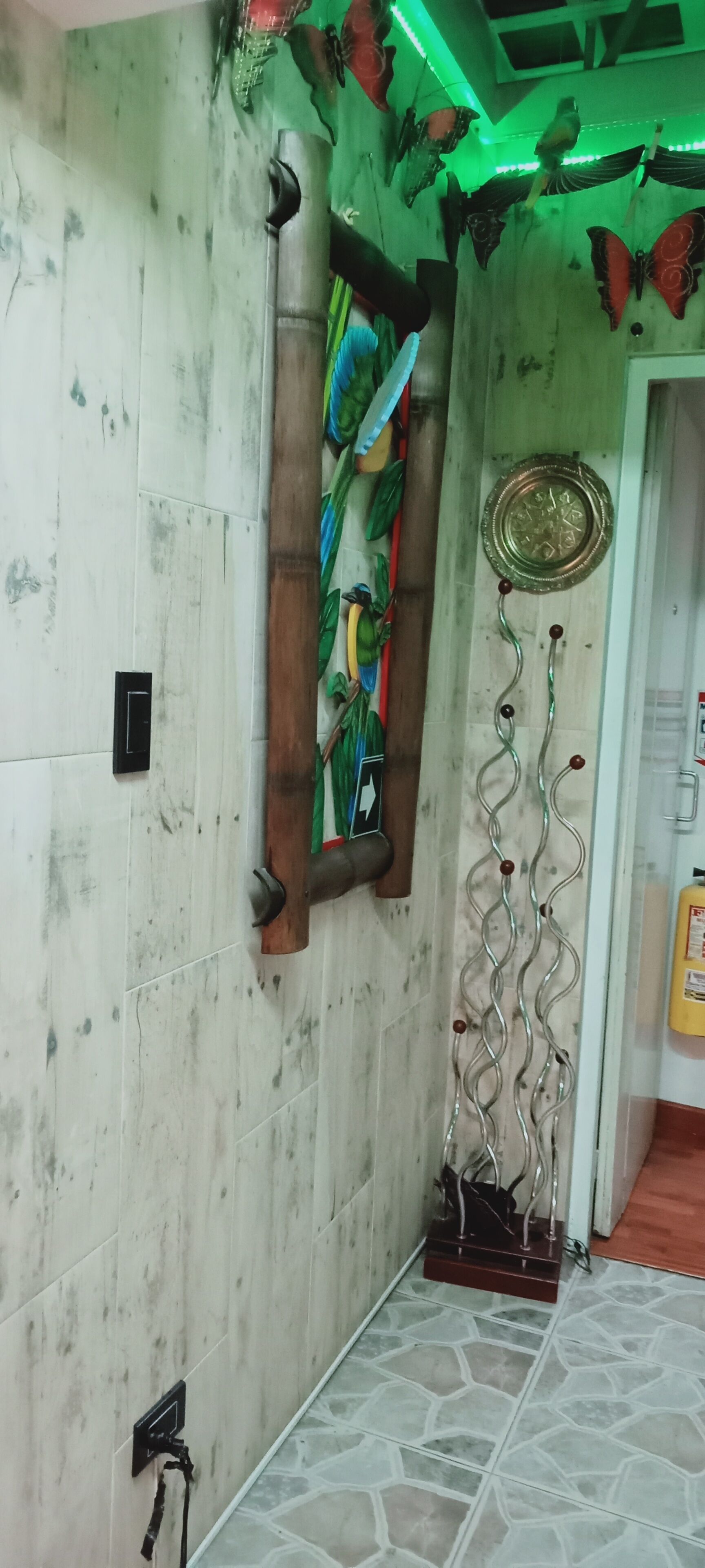 A hallway with a decorative wall, a door with a circular metal plate, and a tiled floor.