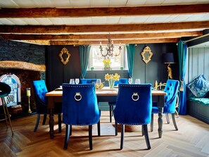 Un comedor con una mesa de madera, sillas tapizadas en azul y un candelabro.