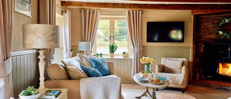 A cozy living room with a sofa, armchairs, a fireplace, and a television.