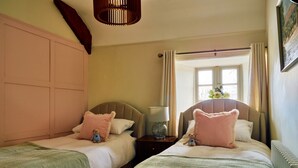 A hotel room with two single beds, each with a pillow and a small teddy bear. There is a nightstand with a lamp between the beds. - Charming Cottage for 4 in Dorset (Brixham)