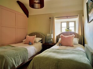 A hotel room with two single beds, each with a pillow and a small teddy bear. There is a nightstand with a lamp between the beds. - Charming Cottage for 4 in Dorset (Brixham)