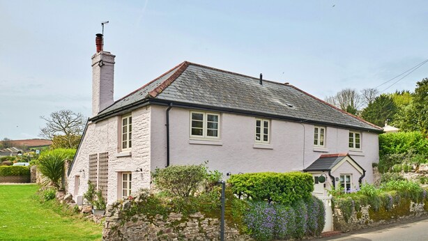 A two-story house with a stone facade, a chimney, and a garden with various plants and flowers. - Charming Cottage for 4 in Dorset (Brixham)