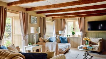 A cozy living room with a sofa, armchair, and a small table with a vase of flowers.
