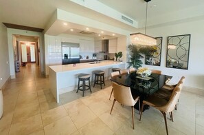 A modern kitchen with a central island, a dining area with a table and chairs, and a hallway leading to another room. - Villa Lakeview - Plantation - Dorado Beach Resort (Dorado)