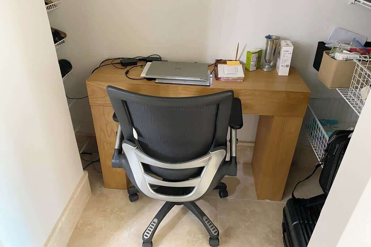 Een werkplek met een bureau, bureaustoel, laptop en diverse spullen op het bureau.
