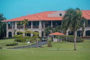Ein Golfplatz mit Clubhaus, Palmen und blauem Himmel.