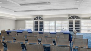 Un salón de conferencias con una larga mesa, sillas y ventanas amplias.