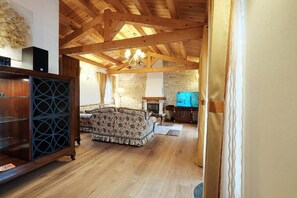 Ein geräumiges Wohnzimmer mit Holzboden, Kamin und Fernseher.