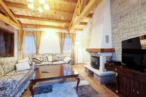 Ein Wohnzimmer mit einer Sofagarnitur, einem Couchtisch, einem Kamin und einem Fernseher.