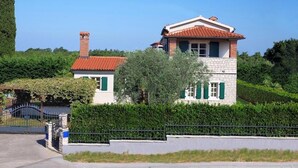 A two-story house with a red-tiled roof, a chimney, and green shutters. - Luxury Villa Le Rose: Pool, Miele Kitchen, Top-Notch Comfort, and Free Bikes! (Poreč)
