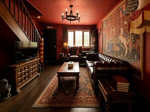 Ein traditionell eingerichteter Raum mit Fernseher, Ledersofa, Teppich mit Muster und einer großen Wandweberei.