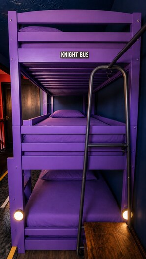 Ein Stockbett mit einer Leiter, beschriftet mit 'KNIGHT BUS', in einem Zimmer mit violetten Wänden und Holzboden.