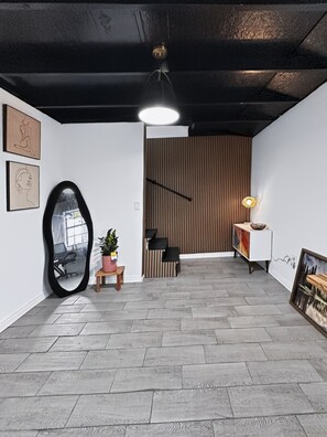 A modern interior with a wooden slatted wall, a large mirror, and a small table with a plant. - Cozy Mountains Retreat w/ Pool-Near Medicine Park & Wichita Mtns - 6091 Pisang (Lawton)