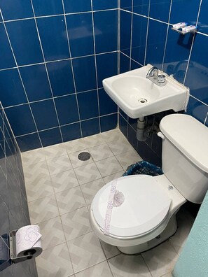 Et badeværelse med toilet, vask og blå flisemur.