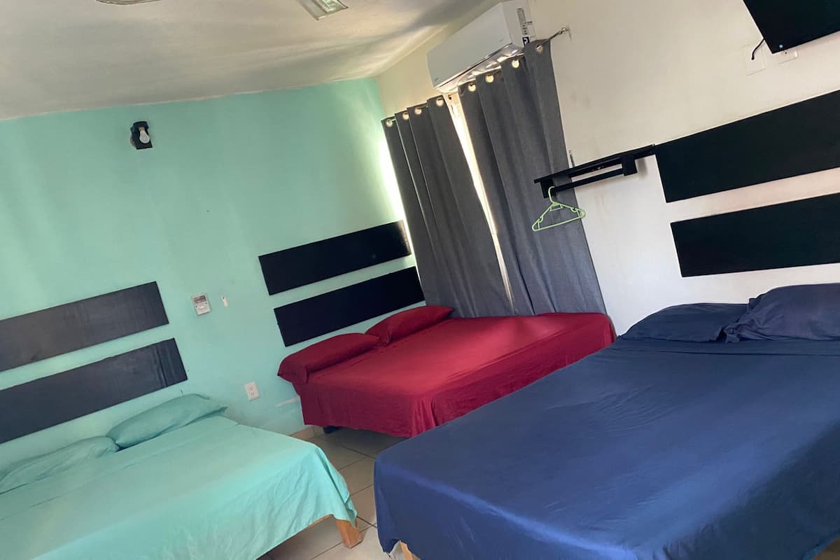 Una habitación con dos camas individuales, una roja, una azul y una verde.