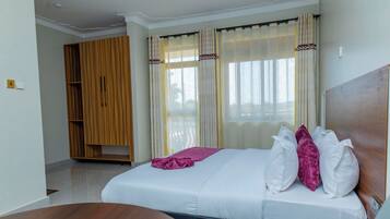 Una habitación de hotel con cama, un armario de madera y una ventana con cortinas.