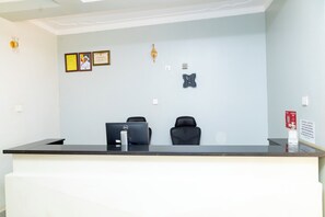 A reception desk with a computer, two chairs, and a notice sign.