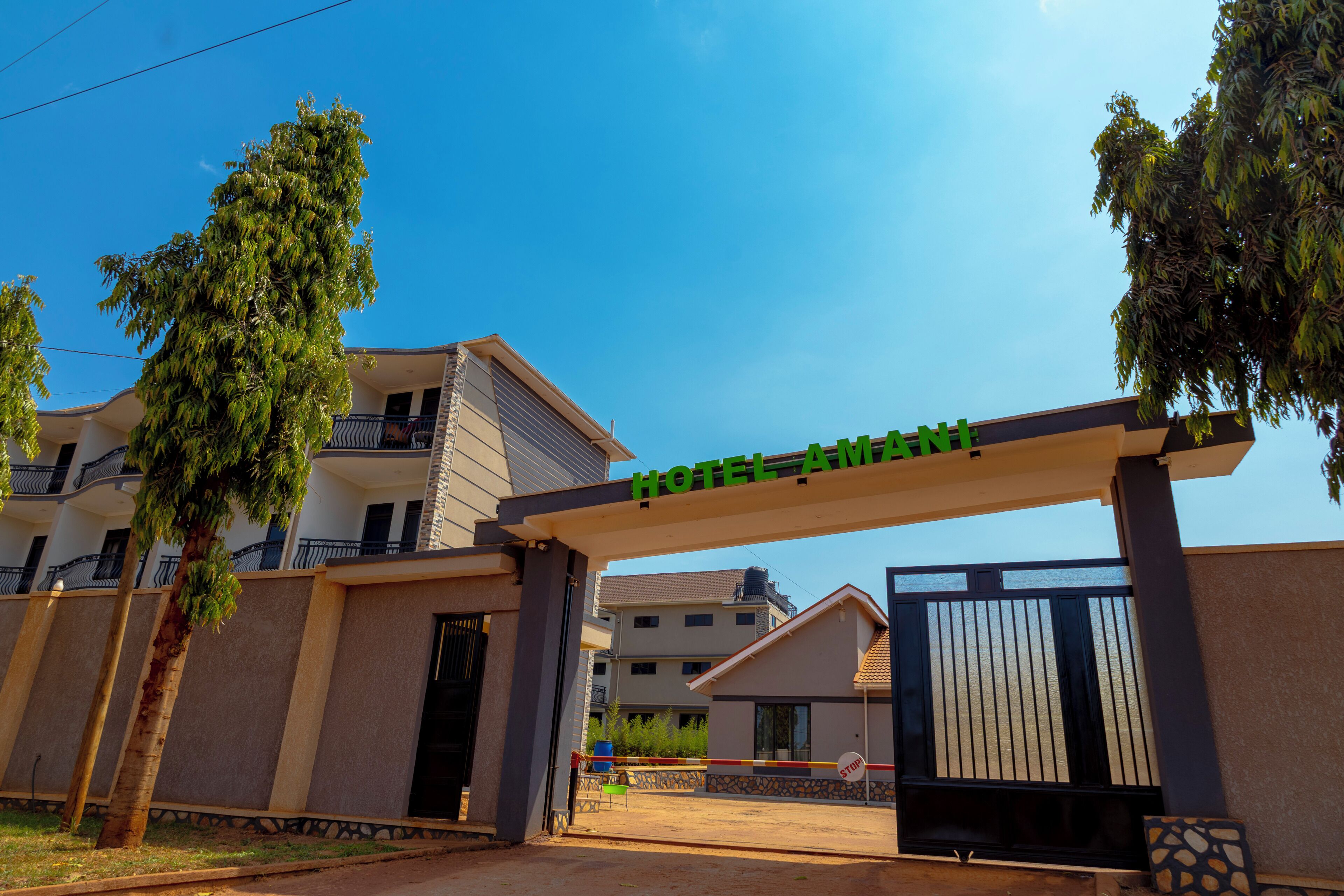 A hotel entrance with a clear sky, a gated driveway, and a sign above the entrance.