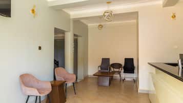 Amplia sala de estar con mostrador de cocina, dos sillones, un sofá y una mesa de comedor.