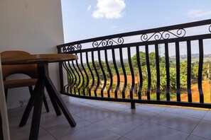 Un balcón con barandilla de metal, una mesa de madera y una silla.