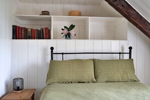 A room with a bed, a nightstand, a shelf with books, and a vase with flowers. - Cottage in Snowdonia National Park (Dolgellau)