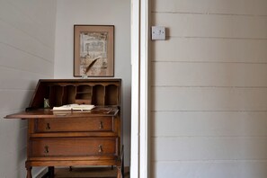 A wooden dresser with drawers and a shelf, a framed calendar on the wall, and a light switch on the door. - Cottage in Snowdonia National Park (Dolgellau)