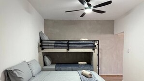 Ein Zimmer mit Etagenbett, Einzelbett, Deckenventilator und Holzboden.