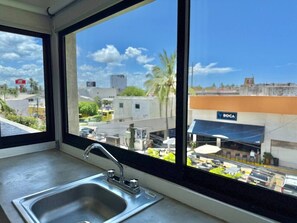 A window with a sink and a view of a cityscape, including a building with a 'BOCA' sign. - Vive la Zona Dorada, Boca de Mar by Partner Host (Mazatlán)